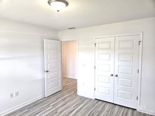 unfurnished bedroom with a closet, a textured ceiling, and light wood-type flooring