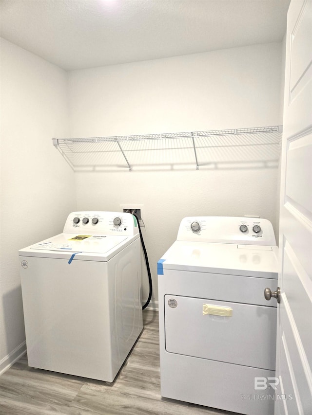 clothes washing area featuring separate washer and dryer and light hardwood / wood-style floors