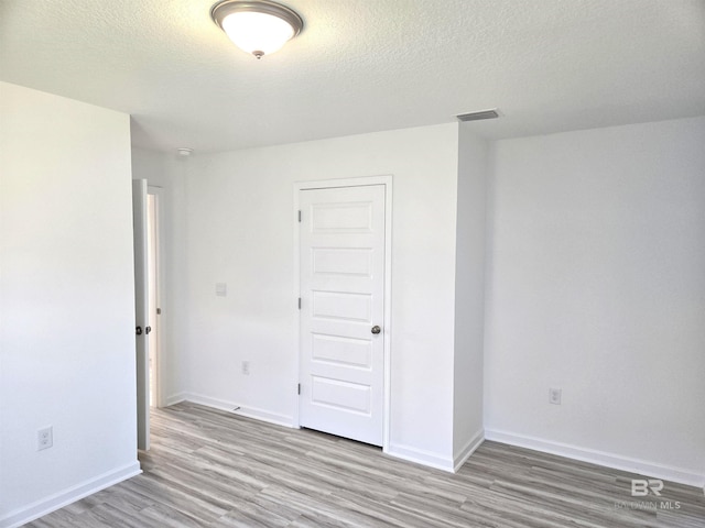 empty room with light hardwood / wood-style floors and a textured ceiling