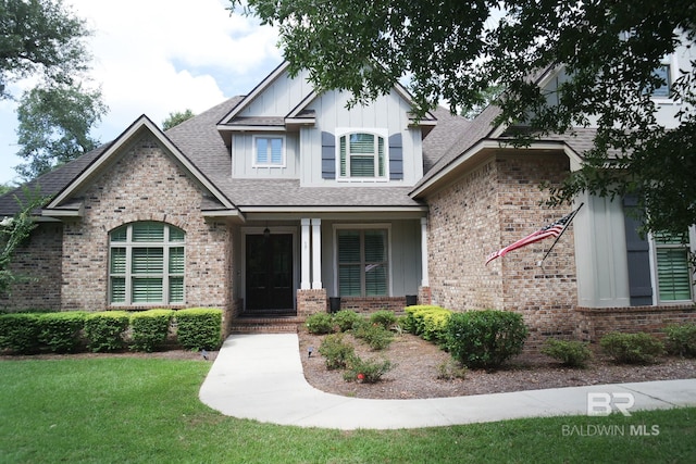 view of front of house featuring a front lawn, board and batten siding, and brick siding