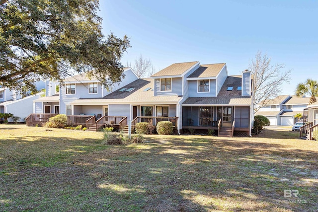 traditional home with a chimney, a front yard, and a wooden deck