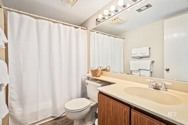 full bathroom with a textured ceiling, toilet, wood finished floors, vanity, and visible vents