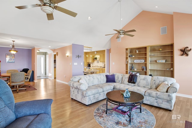 living area featuring a ceiling fan, crown molding, baseboards, and light wood-type flooring