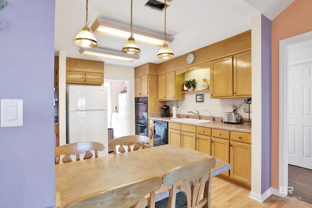 kitchen featuring light wood-type flooring, black appliances, a sink, backsplash, and light countertops