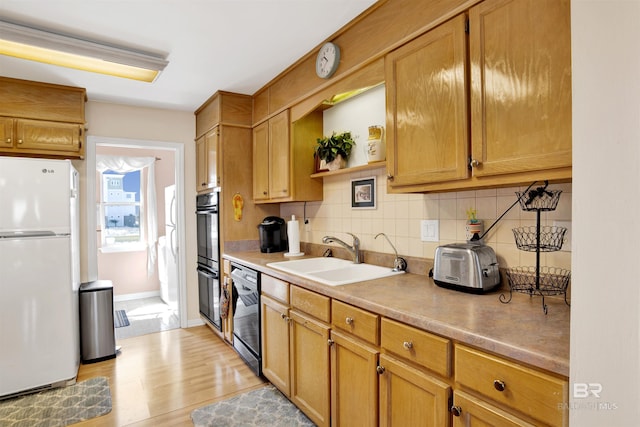 kitchen featuring open shelves, a sink, black appliances, light wood-style floors, and tasteful backsplash