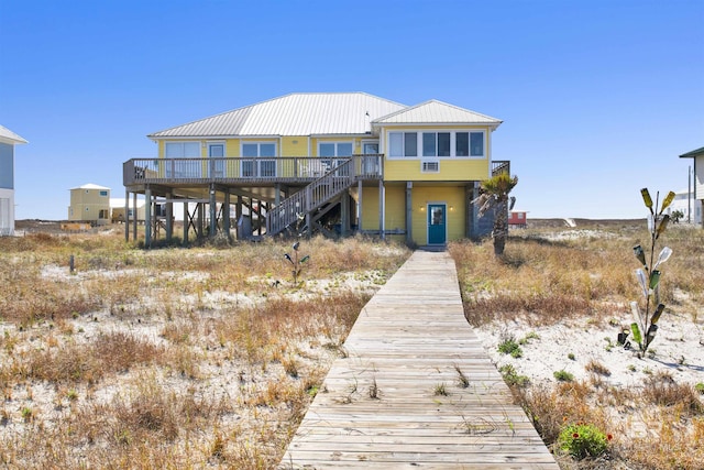 rear view of property featuring metal roof and stairs