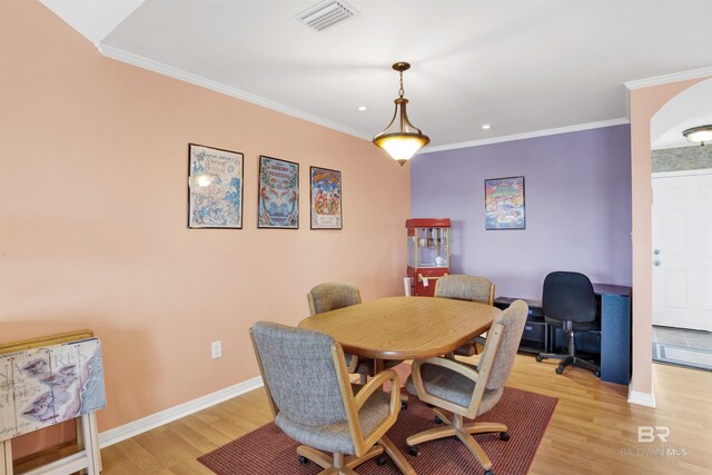 dining area with visible vents, baseboards, light wood-style floors, and ornamental molding