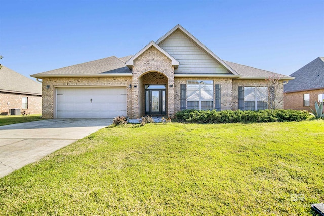 view of front of property featuring brick siding, central air condition unit, an attached garage, and a front yard