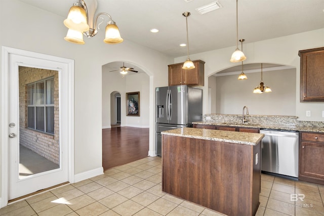 kitchen featuring visible vents, light tile patterned floors, appliances with stainless steel finishes, arched walkways, and a sink