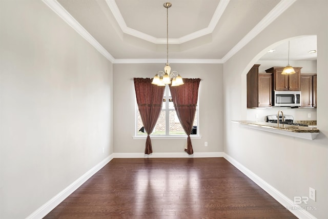 unfurnished dining area with dark wood-type flooring, a notable chandelier, arched walkways, and baseboards