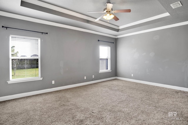 carpeted empty room featuring visible vents, crown molding, ceiling fan, baseboards, and a raised ceiling