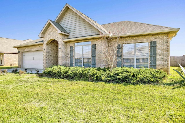 view of front of property with brick siding, a front lawn, fence, roof with shingles, and an attached garage