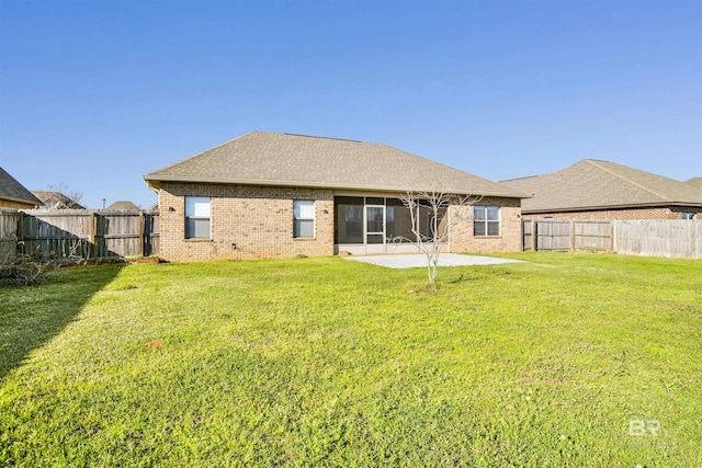 rear view of property with a yard, a patio, brick siding, and a fenced backyard