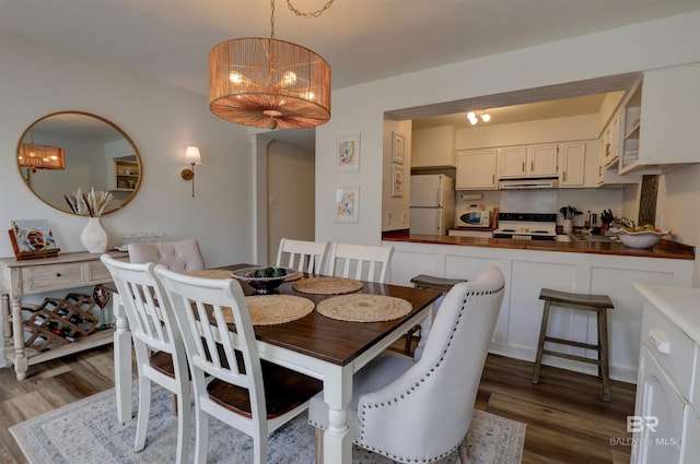 dining area with dark hardwood / wood-style floors and an inviting chandelier