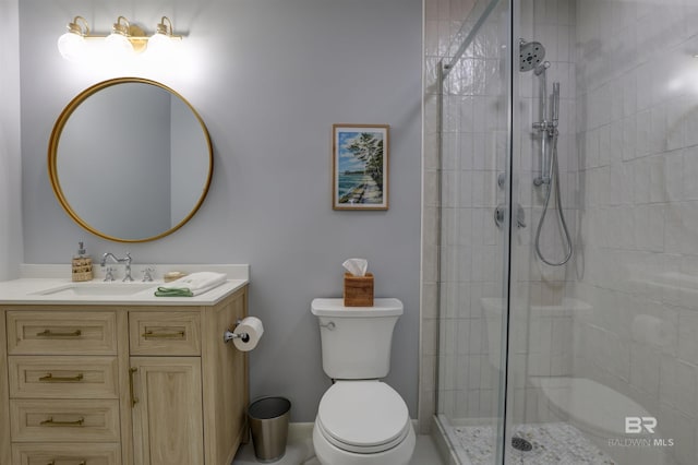 bathroom with tiled shower, vanity, and toilet