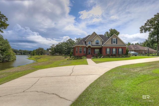 view of front of house featuring concrete driveway, brick siding, a front yard, and a water view