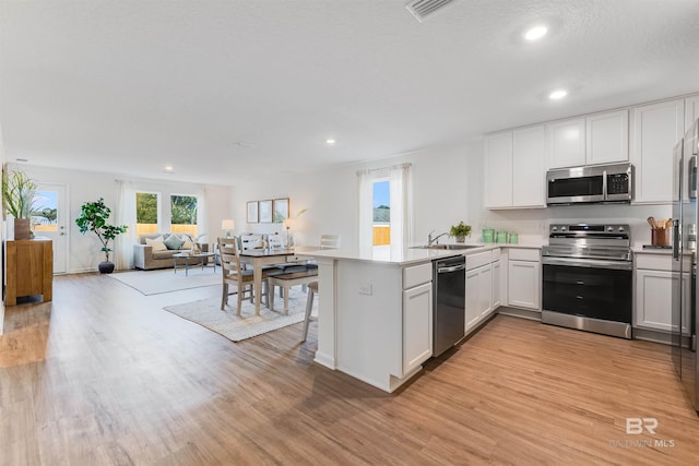 16770 Prado Loop, Loxley, AL 36551 - kitchen featuring appliances with stainless steel finishes, light wood finished floors, a peninsula, recessed lighting, and open floor plan