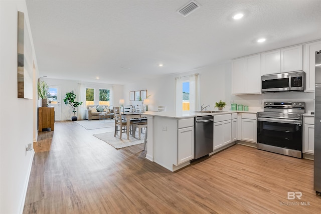 16770 Prado Loop, Loxley, AL 36551 - kitchen featuring appliances with stainless steel finishes, light wood-style flooring, a peninsula, open floor plan, and light countertops