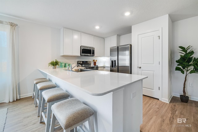 16770 Prado Loop, Loxley, AL 36551 - kitchen featuring appliances with stainless steel finishes, light wood-style flooring, a kitchen breakfast bar, light countertops, and recessed lighting