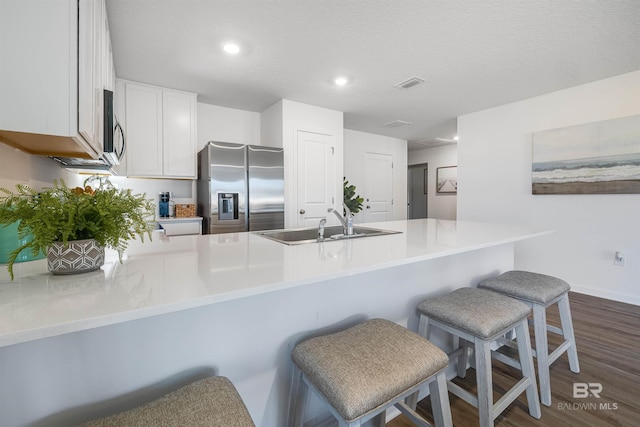 16770 Prado Loop, Loxley, AL 36551 - kitchen with appliances with stainless steel finishes, a peninsula, dark wood-style flooring, white cabinets, and a kitchen bar
