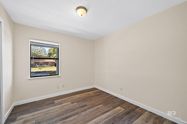 empty room with dark hardwood / wood-style floors and a textured ceiling