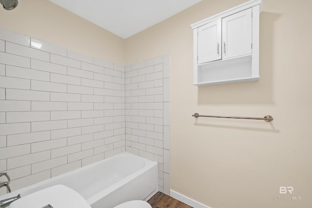 bathroom featuring hardwood / wood-style flooring, toilet, and tiled shower / bath