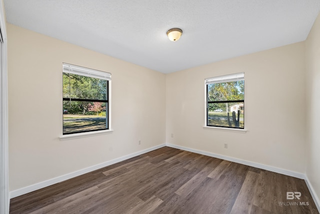 unfurnished room with a textured ceiling and dark wood-type flooring