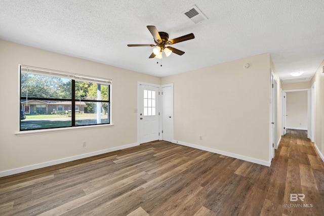 empty room with a textured ceiling, dark hardwood / wood-style flooring, and ceiling fan