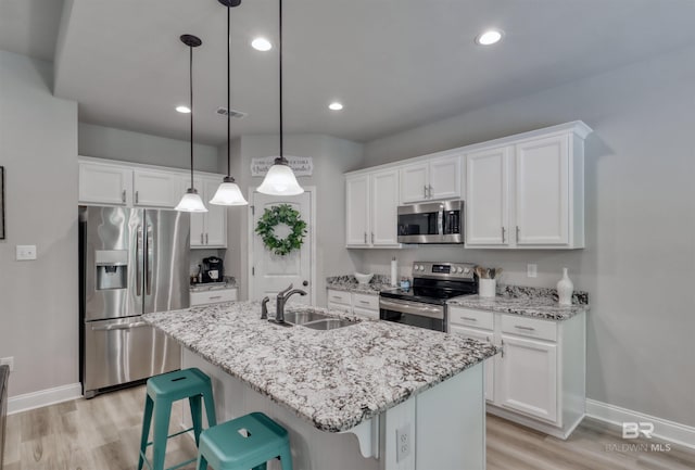 kitchen featuring baseboards, white cabinetry, a sink, light wood finished floors, and appliances with stainless steel finishes