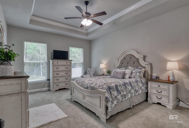 bedroom with crown molding, ceiling fan, light colored carpet, baseboards, and a tray ceiling