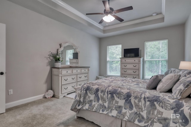 bedroom featuring a ceiling fan, crown molding, baseboards, a tray ceiling, and carpet flooring