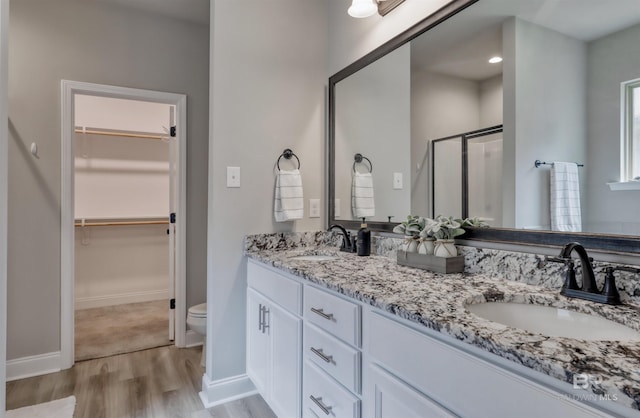 bathroom featuring baseboards, a sink, wood finished floors, and a shower stall