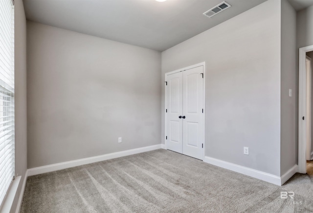 unfurnished bedroom featuring carpet floors, baseboards, a closet, and visible vents