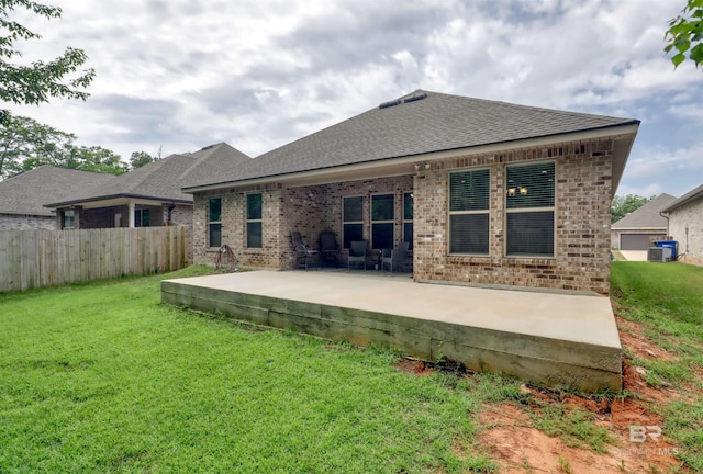 rear view of house featuring roof with shingles, a patio area, brick siding, fence, and a yard