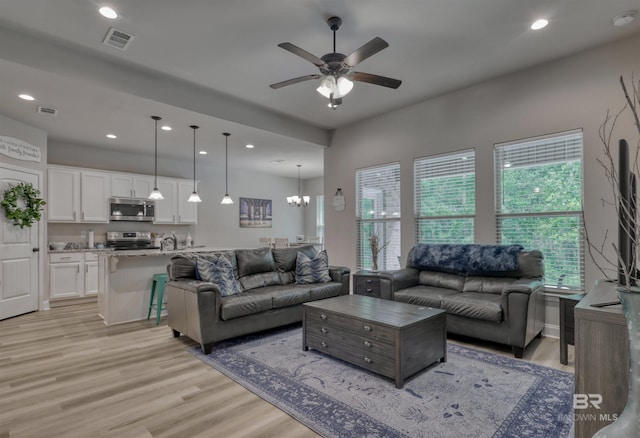 living room with recessed lighting, visible vents, ceiling fan with notable chandelier, and light wood-style floors