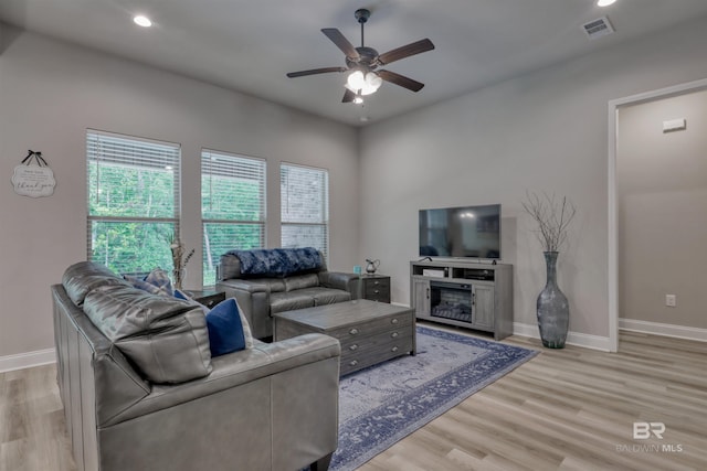 living area featuring visible vents, a ceiling fan, baseboards, and light wood-type flooring