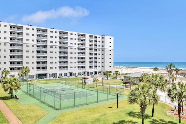 view of sport court with a water view, fence, and a view of the beach