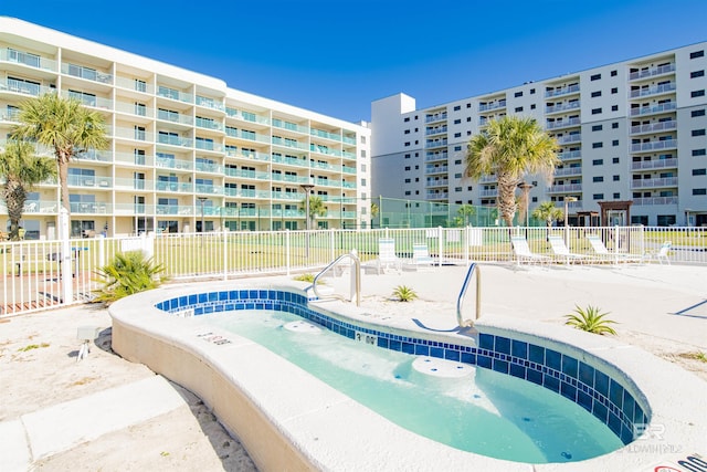 view of swimming pool featuring fence and a community hot tub