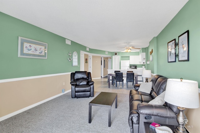 living room with ceiling fan, light carpet, and baseboards