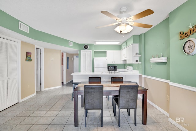 dining space featuring light tile patterned floors, baseboards, visible vents, and ceiling fan