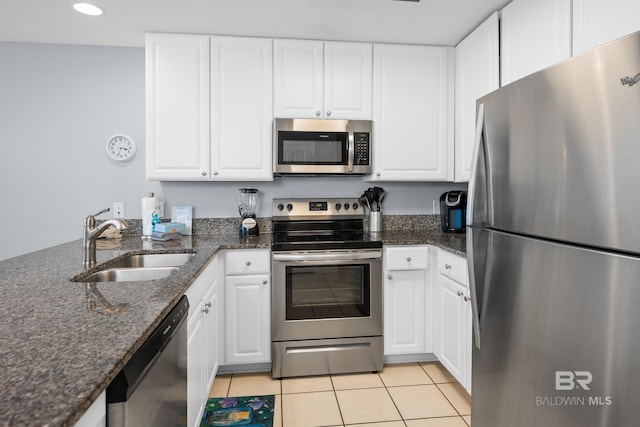 kitchen with appliances with stainless steel finishes, white cabinets, a sink, and light tile patterned floors