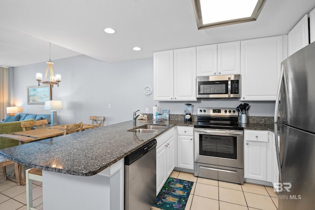 kitchen with stainless steel appliances, light tile patterned flooring, a sink, white cabinetry, and a peninsula