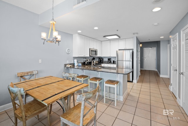 kitchen with light tile patterned floors, stainless steel appliances, a peninsula, a sink, and visible vents