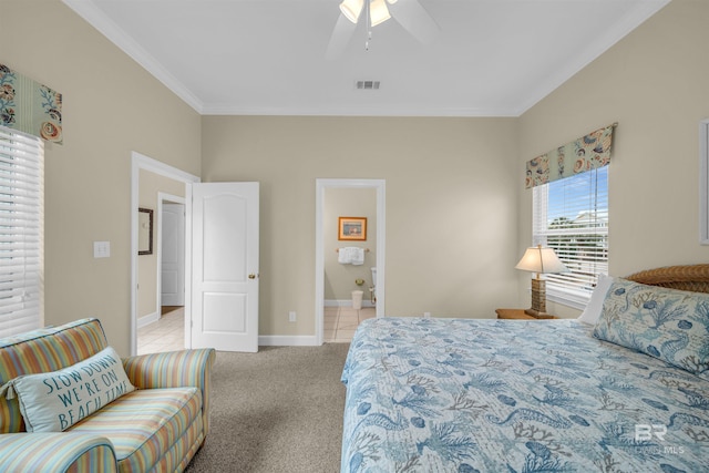 bedroom featuring visible vents, baseboards, light colored carpet, ornamental molding, and ensuite bathroom