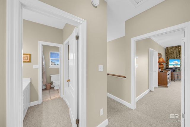 hall featuring baseboards, an upstairs landing, and light colored carpet