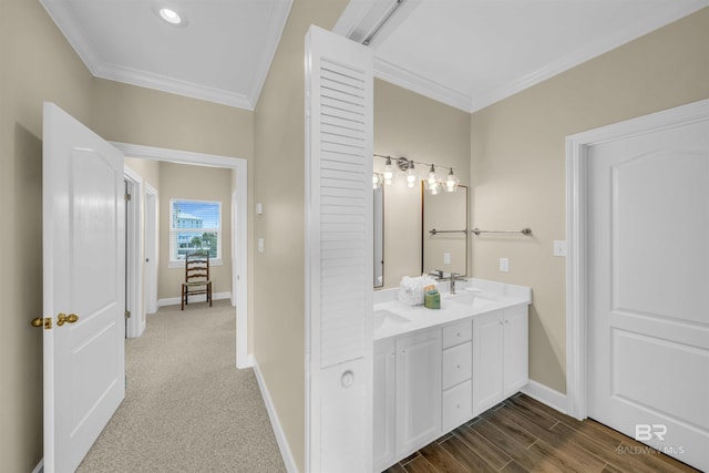 bathroom with wood finished floors, baseboards, double vanity, a sink, and crown molding