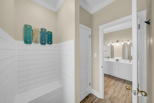 full bath featuring double vanity, ornamental molding, wood finished floors, and a sink