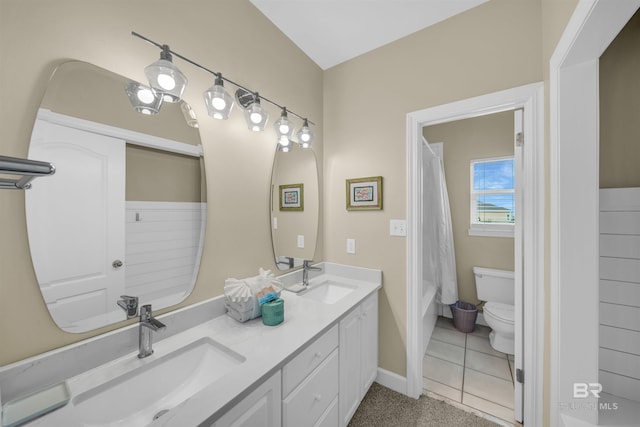 bathroom featuring a sink, baseboards, toilet, and double vanity