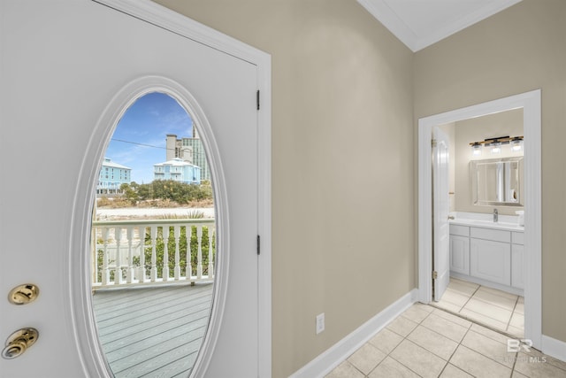 entryway featuring light tile patterned flooring, crown molding, baseboards, and a sink