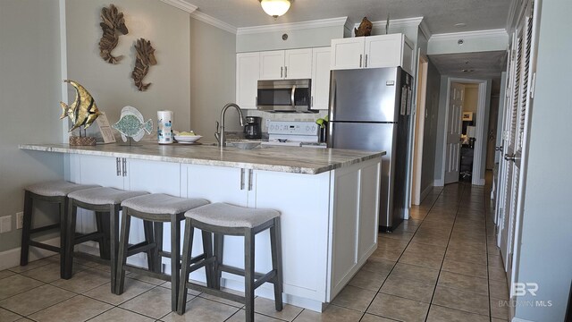 24568 Perdido Beach Blvd Unit 102, Orange Beach, AL 36561 - kitchen with crown molding, stainless steel appliances, a breakfast bar, white cabinets, and light stone countertops